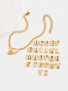 Detail of gold double-layer heart anklet with polished 3D alphabet charms on white stone