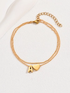 Detail of gold layered ankle bracelet with polished heart and letter A charms