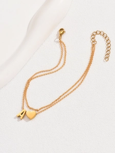 Close-up of golden double-layer anklet featuring heart charm and letter A pendant