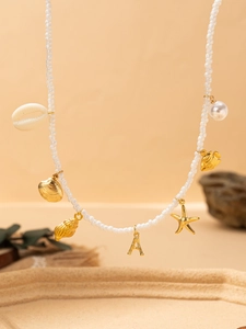 Gros plan sur les breloques de collier de plage avec étoile de mer dorée et perles