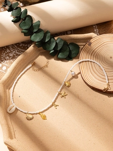Détail du collier de perles avec breloques coquillages dorés et accents de perles