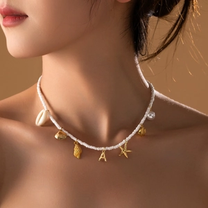 Collier en perles bohème avec breloques coquillages, étoile de mer et initiale A