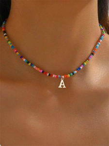 Primo piano di una collana di perline colorate con ciondolo a lettera A in argento su modella