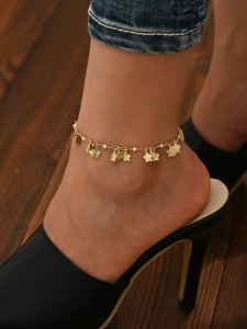 Detail der goldenen Blumen-Fußkette mit Perlen am Knöchel des Modells mit High Heels