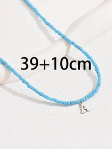 Dettaglio della collana di perline azzurre con ciondolo lettera A e scala di 39+10cm