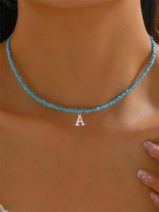 Primo piano di una collana girocollo di perline blu con ciondolo a lettera A d'argento