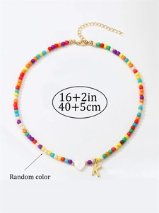 Dettaglio collana di perline colorate con pendente lettera K dorata e ciondolo a cuore