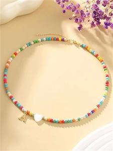 Dettaglio di collana di perline colorate con ciondolo lettera A d'oro e cuore