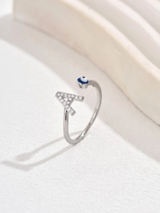 Dettaglio anello regolabile argento con lettera A in cristallo e ciondolo occhio blu