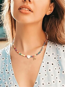 Dettaglio collana di perline colorate con cuore bianco e pendente lettera A dorata