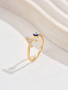 Dettaglio anello dorato con lettera A di cristallo e perla occhio blu greco