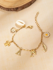 Detail van gouden oceaanarmband met zeeschildpad, dolfijn en madeliefje hangers