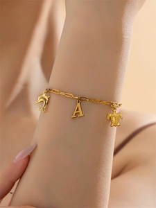 Detailopname van gouden armband met zeedierhangers en letter A voor een vakantie-look