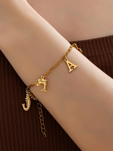 Detail van gouden oceaanarmband met bedeltjes van dolfijn, zeepaardje en de letter A