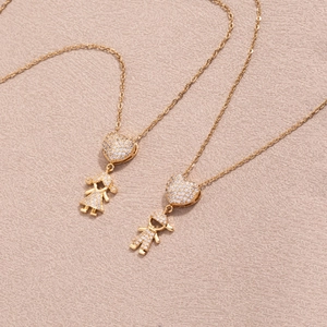 Detailansicht goldener Herzanhänger mit Jungen- und Mädchenfiguren und Zirkoniasteinen