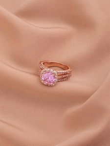 Macro shot of rose gold triple-layer ring with pink halo stone on silk fabric