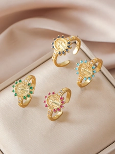 Detailed macro view of four vintage gold rings with religious icons and colorful gemstones