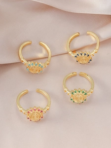 Macro detail of gold Virgin Mary rings with colorful zircon halo on satin fabric
