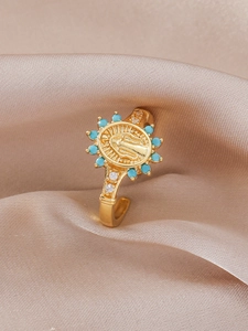 Macro detail of gold religious medal ring with blue beads and zircon on silk