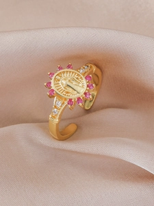Macro shot of gold religious medal ring with pink zircons on champagne silk background