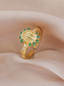 Detail of vintage gold ring with Virgin Mary relief and green faceted emerald-like stones