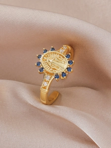 Detail of gold Madonna medallion ring with blue zircons on champagne silk fabric