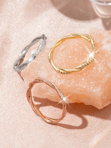 Detailed macro of three-color twisted metal rings with zircon inlay on pink crystal