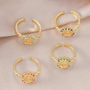 Set of four gold-plated adjustable rings with colored crystals and religious medallions