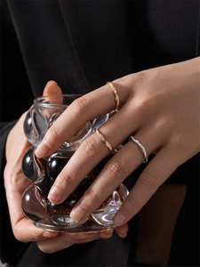 Close-up of stacked gold and silver twisted rings with micro-pave diamonds on a hand