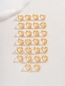 Flat lay of 26 gold flower hollow alphabet open rings from A to Z on white satin