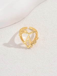 Detailed close-up of golden heart ring featuring letter A and floral petal accents