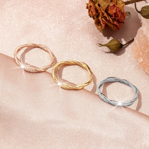 Three twisted pavé eternity rings in rose gold, gold, and silver on champagne silk fabric