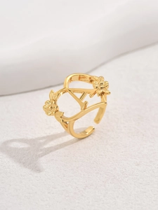 Detailed close-up of golden open ring with hollow letter A and delicate flower design