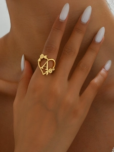 Detailed view of heart-shaped hollow gold ring with flower engraving and letter A detail