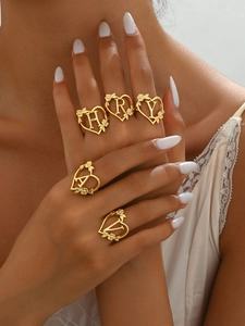 Detailed shot of gold heart-shaped rings with floral engraving and alphabet initials