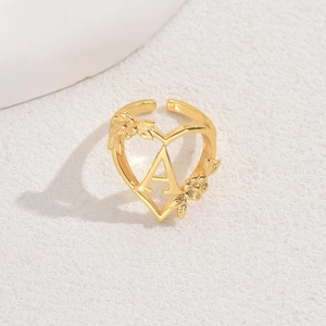 Adjustable golden heart ring featuring letter A with floral accents on stone background