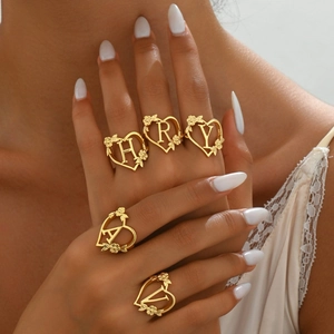 Golden open heart ring with hollow letter and floral accents shown on hand