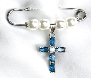 Detail view of silver safety pin brooch with white pearls and blue gemstone cross charm