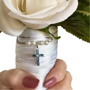 Elegant pearl pin with blue marquise gemstone cross pendant on white satin floral