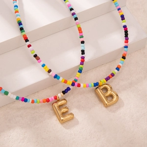 Collana boho fatta a mano con perline colorate e ciondoli a forma di lettera dorata
