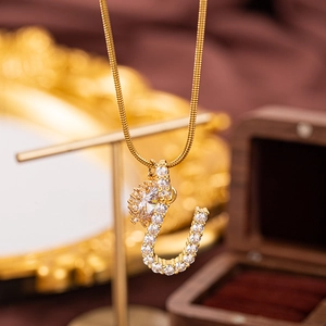 Detailaufnahme einer goldenen Schlangenkette mit einem zirkonia-besetzten J-Buchstaben