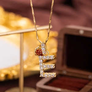 Gold letter E pendant necklace with clear crystals and a red heart accent
