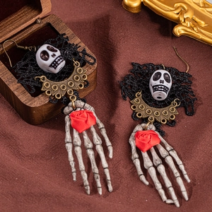 Detailed shot of gothic skull earrings with black lace and red roses on wooden box