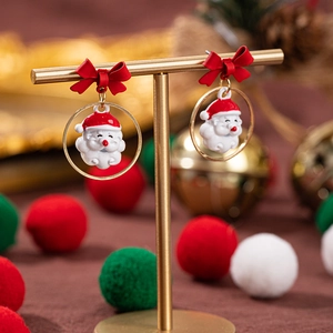Vista dettagliata di orecchini natalizi con Babbo Natale e fiocchi rossi su supporto oro