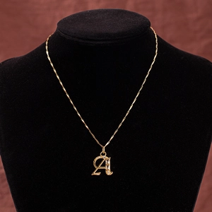 Macro shot of gold letter A pendant with clear cubic zirconia on a black velvet bust