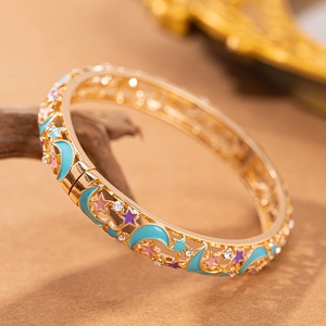 Dettaglio del bracciale traforato in oro con smalto stella luna e strass scintillanti