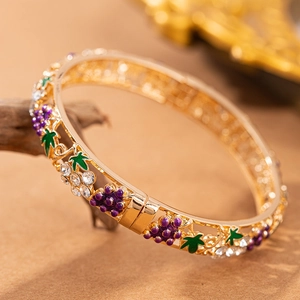 Dettaglio del bracciale vintage in oro traforato con uva in smalto viola e foglie verdi