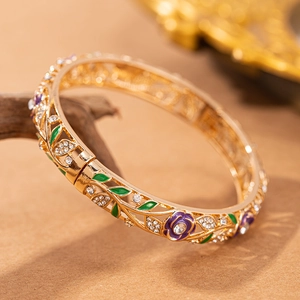 Dettaglio di un bracciale dorato vintage con rose in smalto viola e cristalli intarsiati