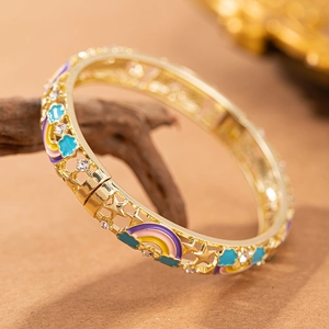 Dettaglio del bracciale dorato traforato con ciondoli a arcobaleno colorati e stelle