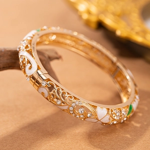 Dettaglio macro del bracciale rigido dorato vintage con smalto bianco e zirconi lucidi